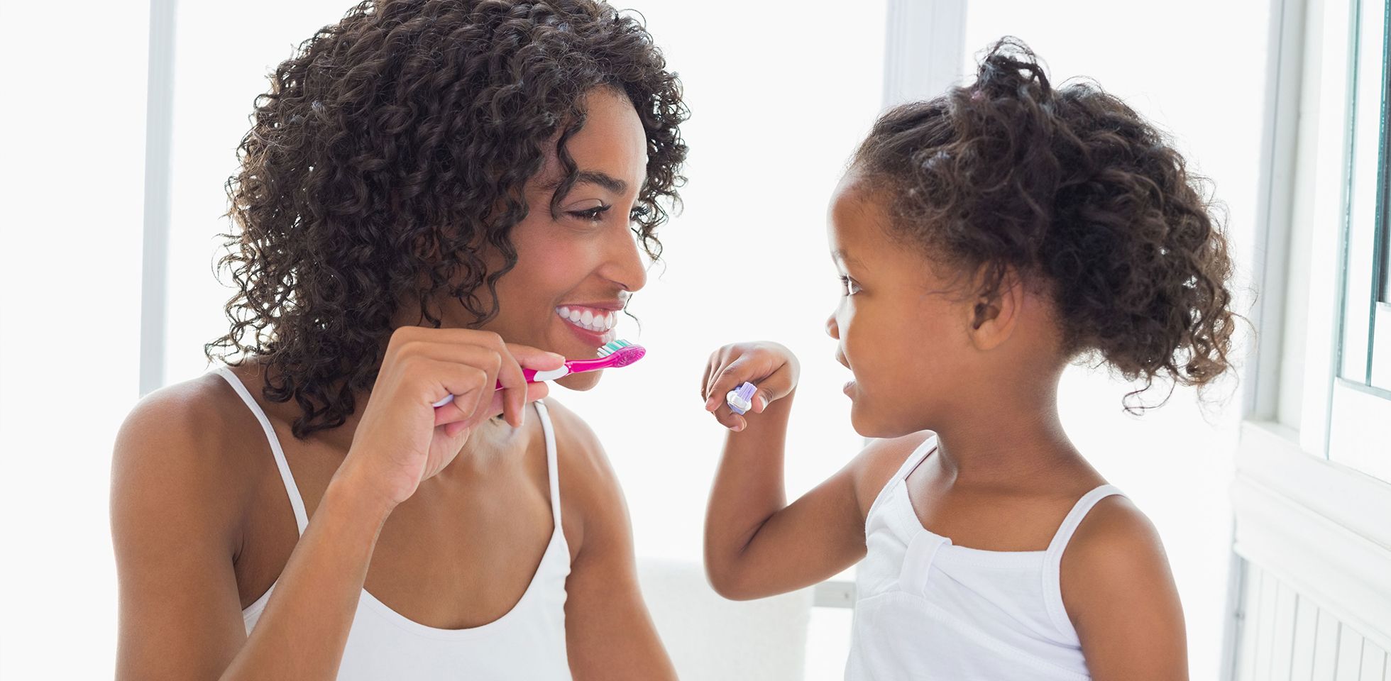 A parent brushing their teeth with their child before going to a pediatric dentist in NYC