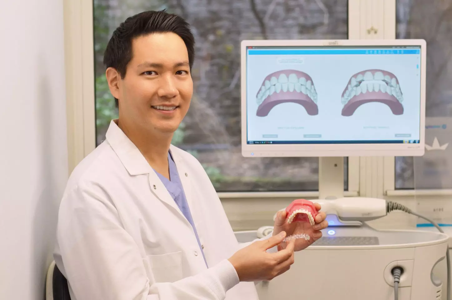 A NYC dentist holding Invisalign aligners